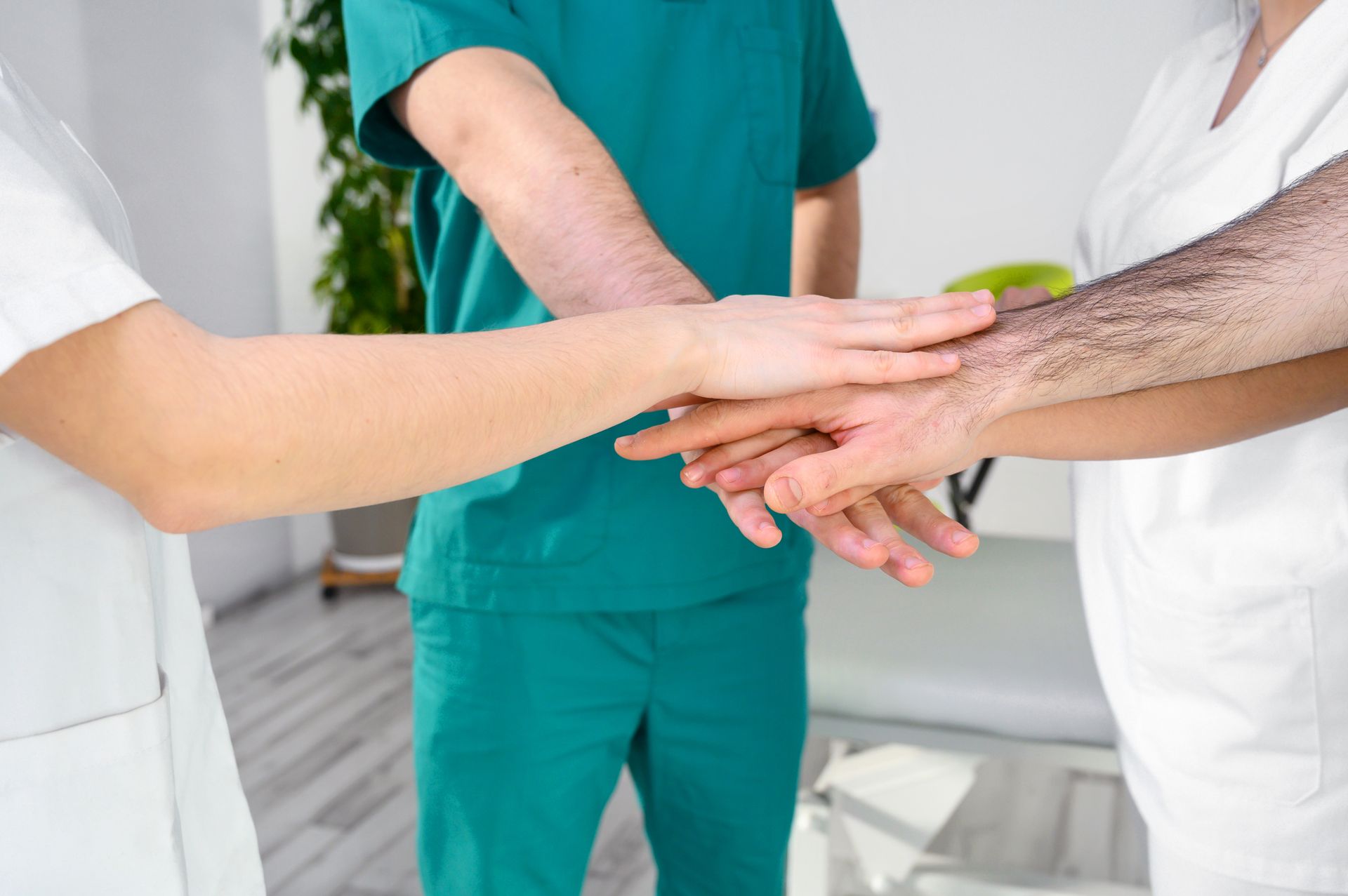 a group of doctors and nurses are putting their hands together .